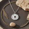 Silver Shema Yisrael nano Bible necklace on a dark tray, a meaningful Jewish gift