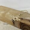 Gold Am Yisrael Chai necklace resting against olive wood