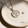 White gold Am Yisrael Chai disc necklace in a pale ceramic dish