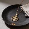 Yellow gold Am Yisrael Chai disc necklace on a black plate
