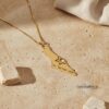 Solid gold map of Israel necklace on a stone ledge