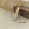 Gold Shema Israel map necklace resting against olive wood