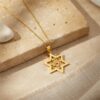 Yellow gold Star of David necklace draped over travertine