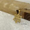 Gold Star of David pendant against patterned marble and wood