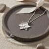 White gold Star of David necklace on a brown ceramic plate
