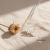 Am Yisrael Chai silver pendant photographed beside a dried rose