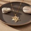 Layered gold Shema star necklace on a brown ceramic plate