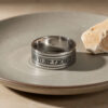 Sterling silver Hebrew verse ring on a gray stone dish