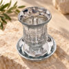 Crystal kiddush cup with matching saucer on a stone surface with olive leaves