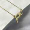 24K gold plated Hebrew name necklace on a stone surface, close up
