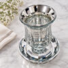 Crystal kiddush cup with saucer beside white flowers on marble, angled view of the silver finish