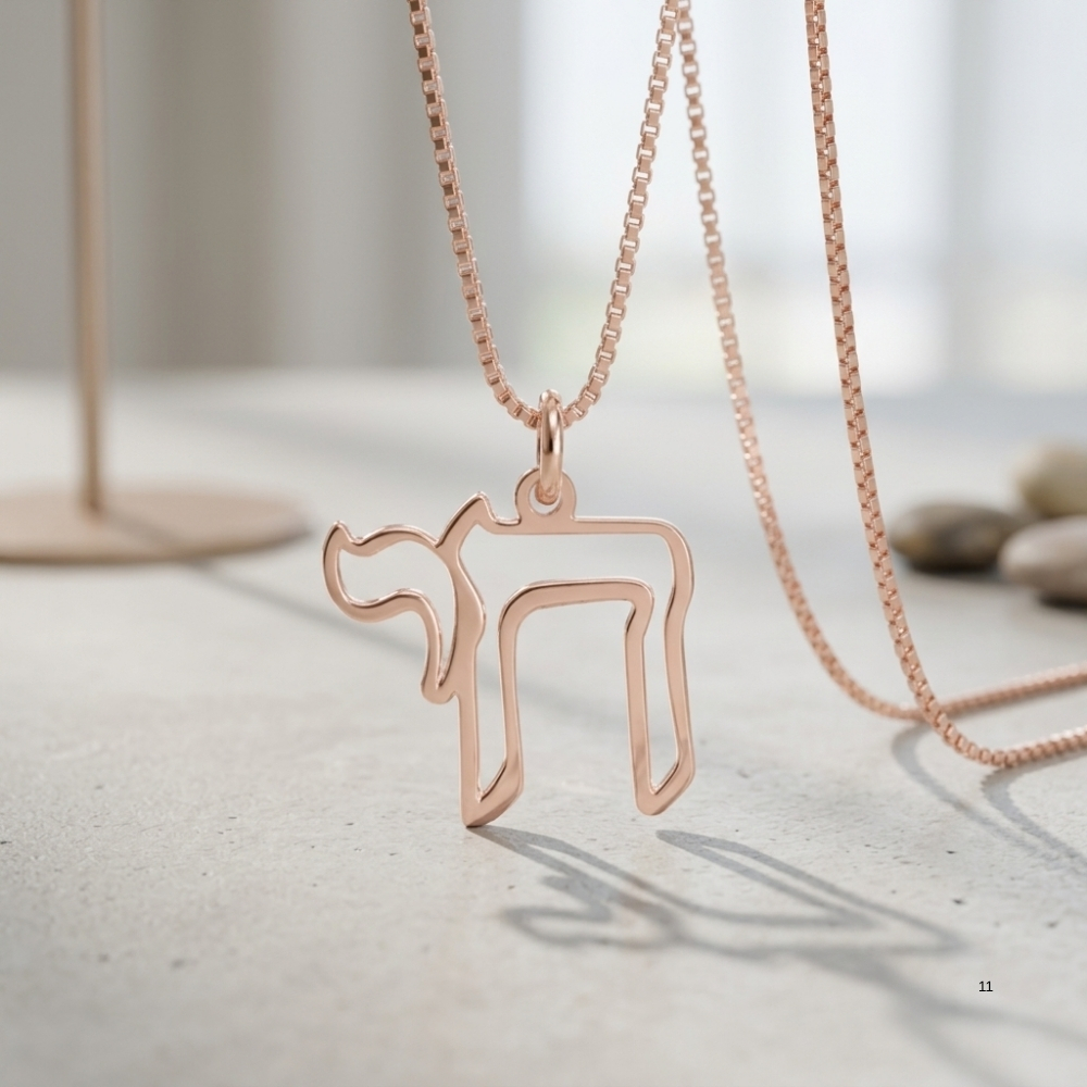 Rose gold open outline Chai necklace hanging over a light stone surface