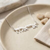 Sterling silver Hebrew name necklace in a ceramic dish with pebbles