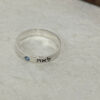 Close up of a sterling silver Hebrew name ring with blue birthstone