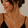 Woman wearing a dainty sterling silver Hamsa evil eye necklace with a black top