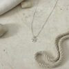 Sterling silver mini Chai necklace laid flat on handmade paper