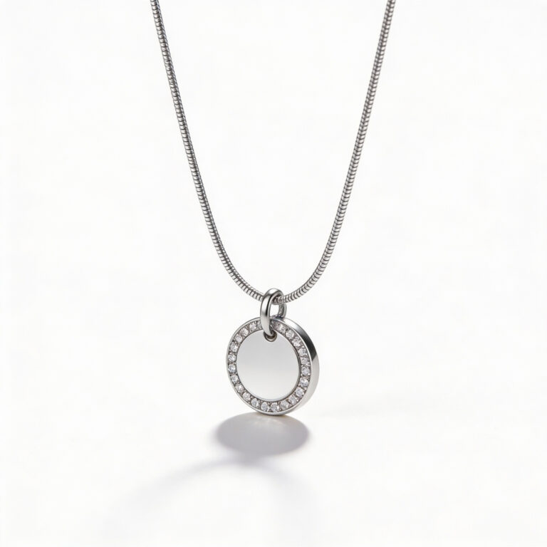 Silver tone stainless steel round pendant framed by a halo of zircon stones on a snake chain, white background