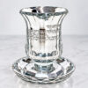 Crystal kiddush cup and saucer on a white marble surface, fluted sides and faceted stem
