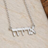 Close up of a sterling silver Hebrew name pendant on a stone surface