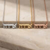 Hebrew name necklaces in silver, gold and rose gold laid on travertine stone