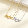 Pair of 14K gold heart nameplate necklaces in yellow and white gold, laid on cream marble