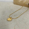 Gold zircon halo pendant on a gold snake chain on a stone surface