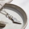 Israel Map Necklace with Engraved Bible Verse — pendant coiled with its chain on a stone dish