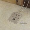 Engraved silver dog tag necklace angled on textured ground