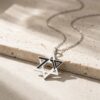 Sterling silver October 7 memorial Star of David pendant lying on Jerusalem stone in sunlight