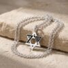 Silver October 7 Star of David necklace with its chain coiled on Jerusalem stone