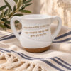 Netilat Yadayim Jewish washing cup in white polymer with gold Hebrew blessing and brown base, on a striped linen cloth with olive branches