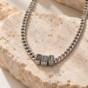 Hebrew name necklace for dad, silver tone Cuban chain with three engraved name beads resting on natural travertine stone