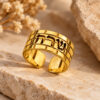 Hebrew name ring in 14K yellow gold with Western Wall brick texture on travertine stone beside dried flowers