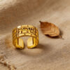Gold Hebrew name ring with Western Wall texture on natural linen next to a dried leaf