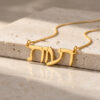 Yellow gold Hebrew nameplate necklace resting on a stone ledge in soft natural window light.