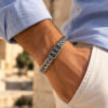 Wrist close up of a men's wheat chain bracelet with engraved Hebrew name beads