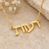 Angled close-up of a 14K gold Hebrew name pendant reading Reut, showing the depth of the gold letters.