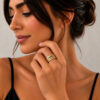 Woman wearing a 14K yellow gold Hebrew name ring with Western Wall texture on her hand near her face